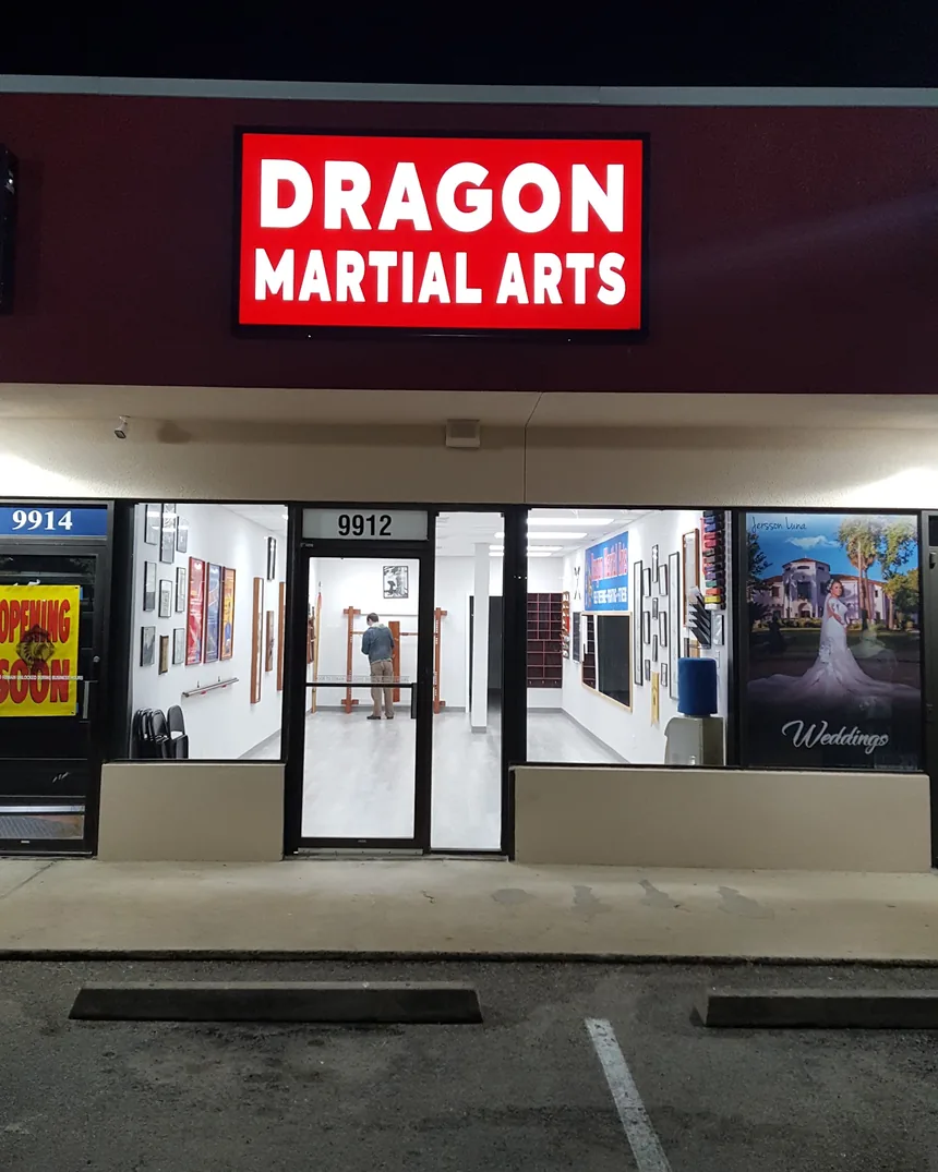 The illuminated Dragon Martial Arts sign above the entrance at night